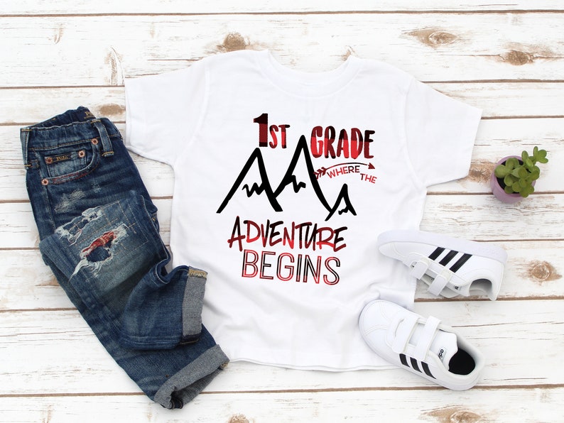 May include: White t-shirt with black text that reads "1st Grade Where the Adventure Begins" with a red and black mountain graphic.