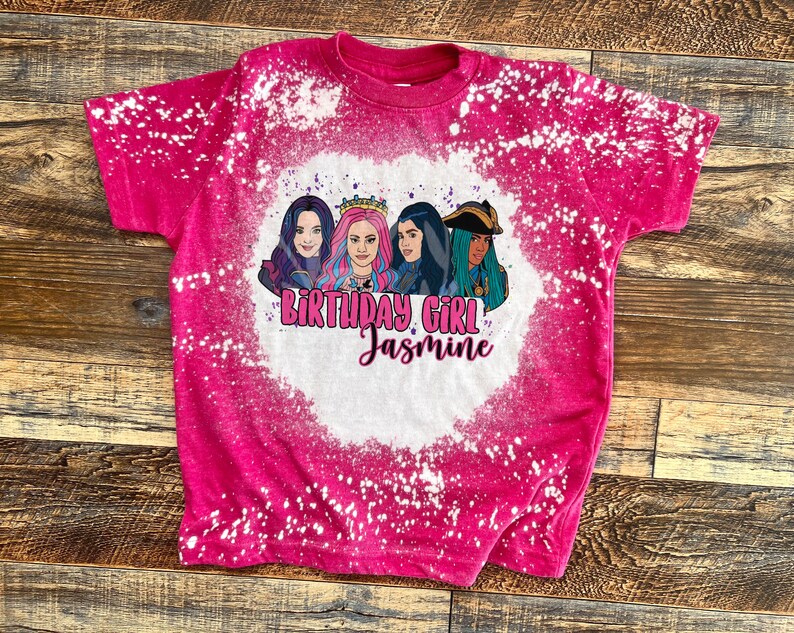 May include: Pink t-shirt with a bleach-splattered design featuring a group of cartoon characters and the text "Birthday Girl Jasmine".