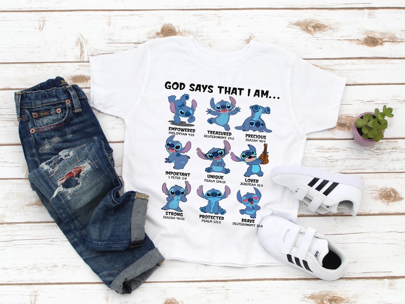May include: White t-shirt with a blue cartoon character, Stitch, in different poses. Each pose has a bible verse and a word describing Stitch, such as "empowered", "treasured", "precious", "important", "unique", "loved", "strong", "protected", and "brave". The text "GOD SAYS THAT I AM..." is at the top of the shirt.