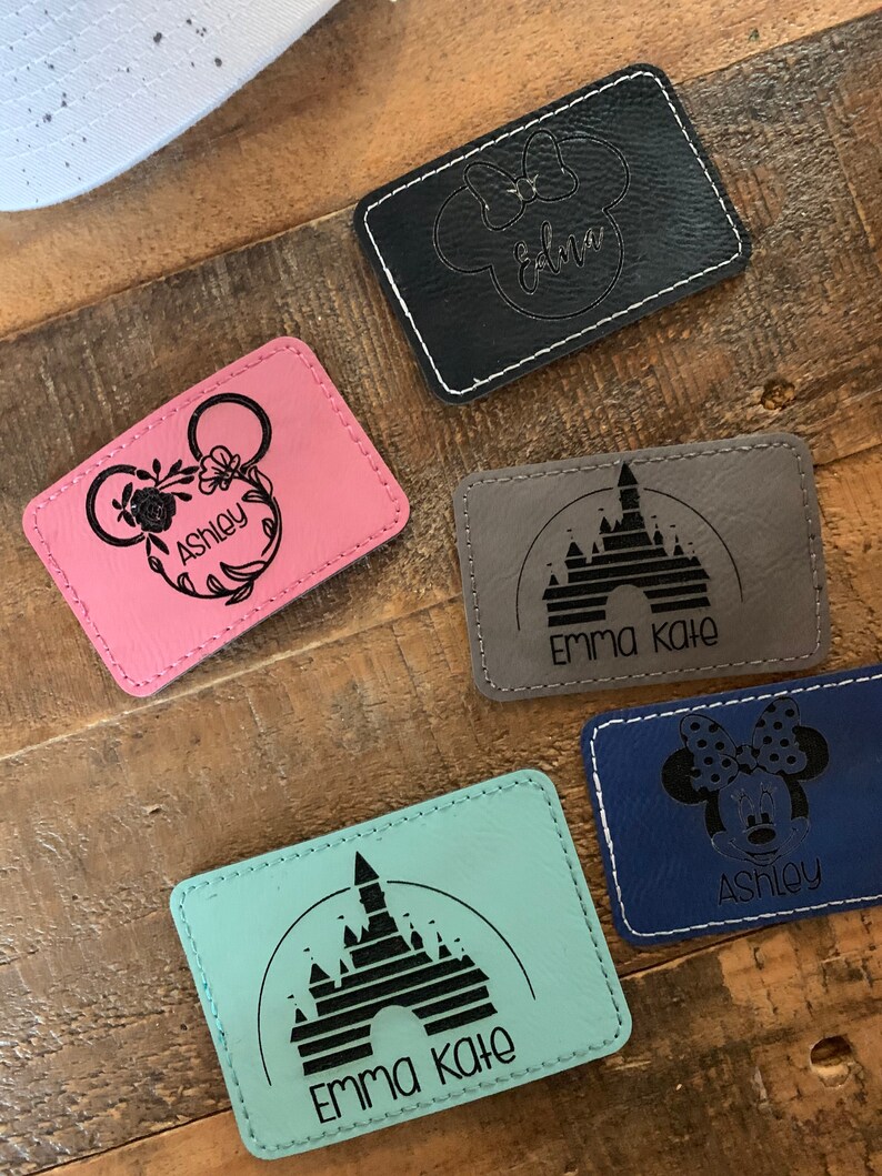 Pu&ograve; includere: Cinque toppe in pelle personalizzate con diversi design di personaggi Disney e nomi. Le toppe sono di vari colori, tra cui rosa, nero, grigio, blu e turchese. I nomi sulle toppe includono Ashley, Edna, Emma Kate e Ashley.