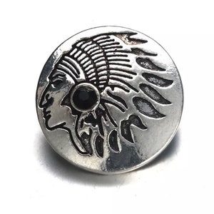 Puede incluir: Botón de metal plateado con un perfil detallado de un nativo americano que lleva un tocado con una piedra preciosa negra en el centro.