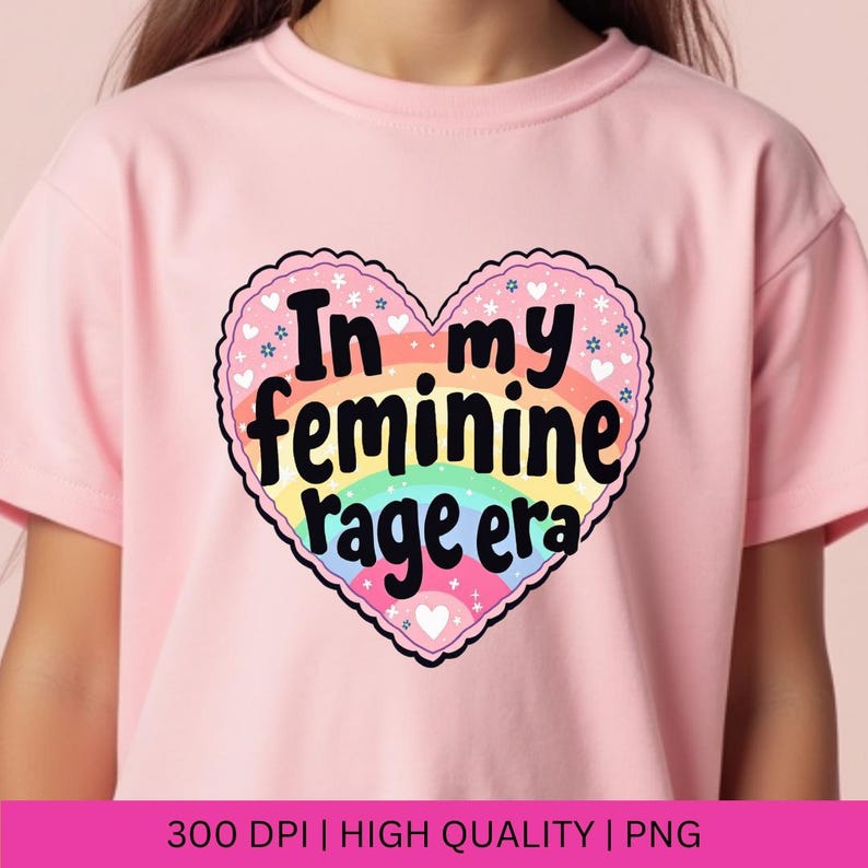 May include: Pink t-shirt with a rainbow heart graphic that says "In my feminine rage era".
