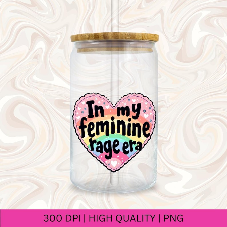 May include: A clear glass jar with a bamboo lid and a straw. The jar has a pink heart sticker with the text "In my feminine rage era" in black lettering. The heart sticker has a rainbow design.