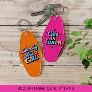 May include: Two pink and orange keychains shaped like motel keys. One keychain says "Get in Loser" in rainbow letters with stars. The other keychain says "Literally Just a Girl" in rainbow letters with stars.