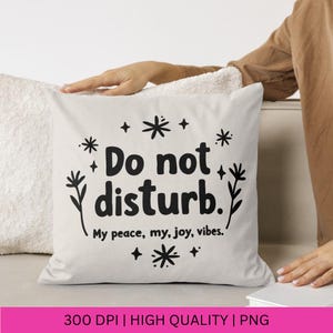 Puede incluir: Almohada blanca con texto negro que dice "No molestar. Mi paz, mi alegr&iacute;a, mis vibraciones." con peque&ntilde;as ilustraciones de flores negras a cada lado del texto.