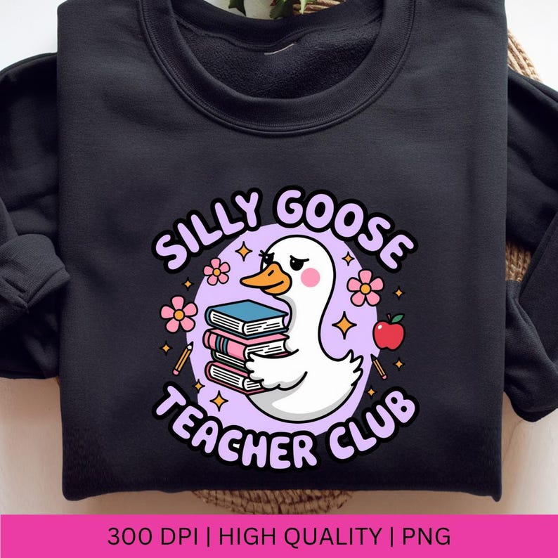 Op de afbeelding: Zwart sweatshirt met een afbeelding van een witte gans die boeken vasthoudt, omringd door bloemen, sterren en een appel. De tekst luidt "Silly Goose Teacher Club".
