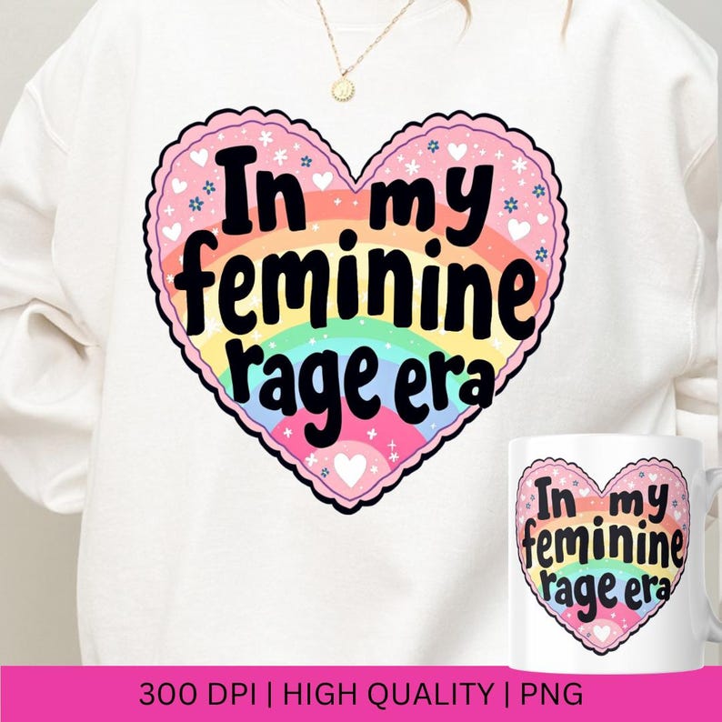 May include: A white sweatshirt with a rainbow heart design. The heart has the text "In my feminine rage era" in black lettering.