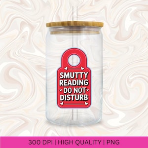 Pu&ograve; includere: Un bicchiere di vetro trasparente con coperchio in bamb&ugrave; e una grafica rossa a forma di etichetta. La grafica recita "Smutty Reading Do Not Disturb" in testo bianco, con accenti a cuore. Una cannuccia &egrave; visibile all'interno del bicchiere.