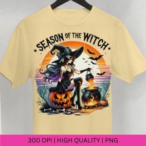 May include: A yellow t-shirt featuring a graphic of a witch stirring a cauldron with a pumpkin and bats in the background. The text "Season of the Witch" is written in a black font.
