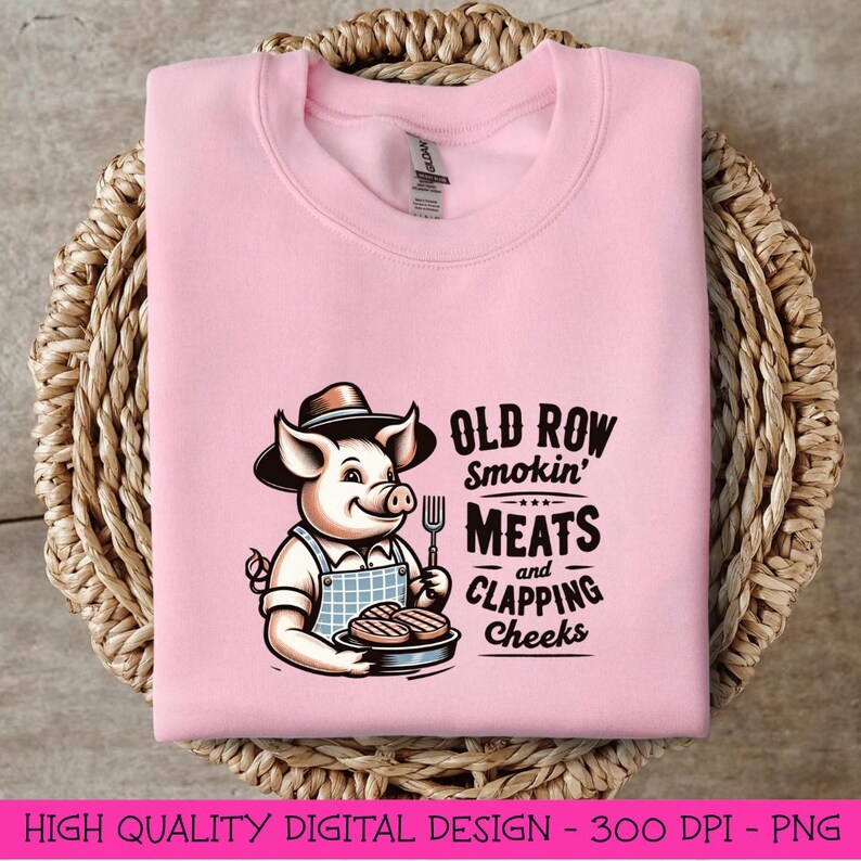 May include: Pink sweatshirt with a cartoon pig wearing a hat and holding a plate of grilled meat. The text "Old Row Smokin' Meats and Clapping Cheeks" is printed on the shirt.