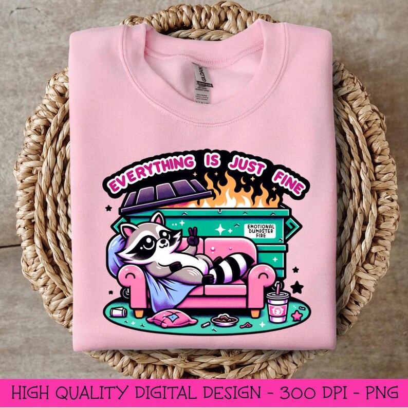 May include: A pink sweatshirt with a graphic design of a raccoon sitting on a couch in front of a dumpster fire. The text "Everything is just fine" is written above the dumpster.