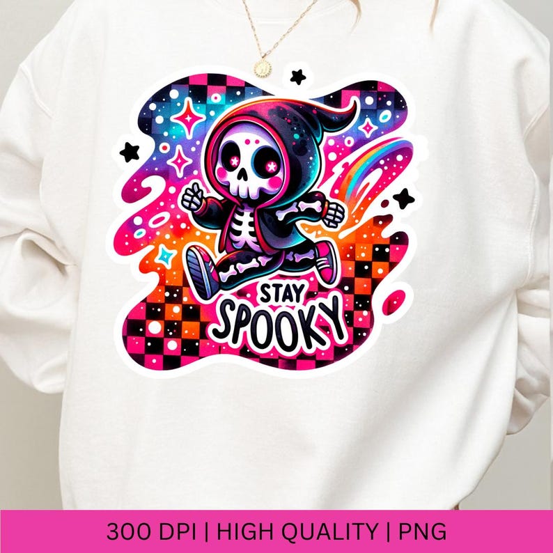 May include: A white sweatshirt featuring a colourful graphic of a skeleton wearing a hooded cloak and running. The graphic has a rainbow and stars in the background. The text "Stay Spooky" is below the skeleton.