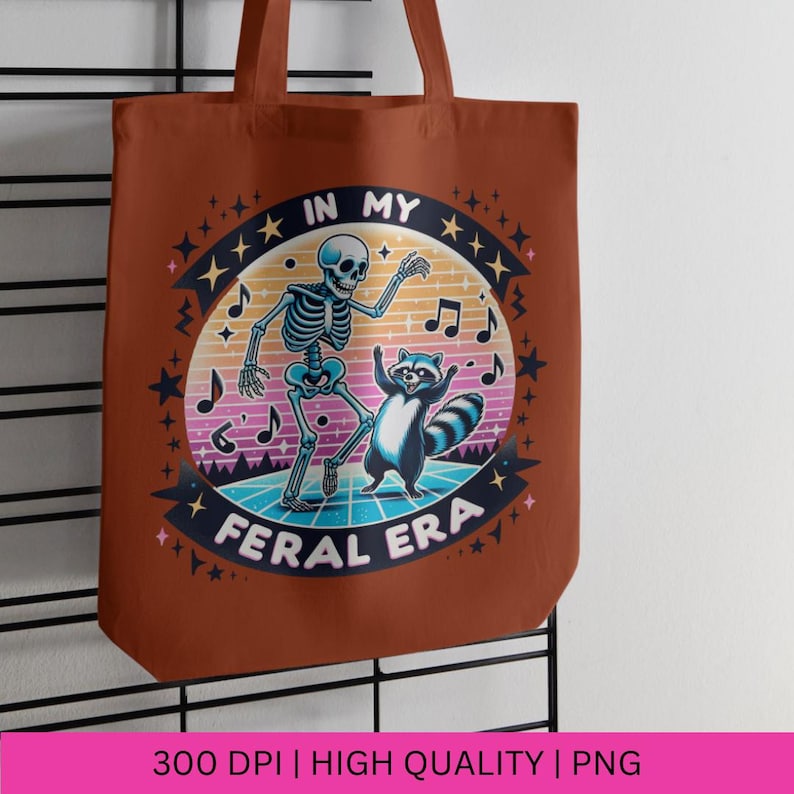 May include: A brown tote bag featuring a graphic of a skeleton and a raccoon dancing on a retro-style dance floor. The text "In My Feral Era" is printed in a circle around the graphic.