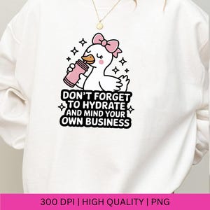 May include: White sweatshirt featuring a cartoon duck with a pink bow, holding a pink water bottle. The text "DON'T FORGET TO HYDRATE AND MIND YOUR OWN BUSINESS" is printed below the duck. The design includes black stars.