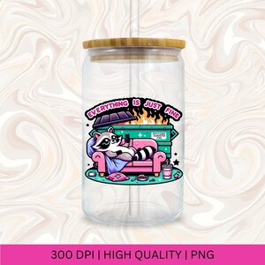 May include: A clear glass jar with a bamboo lid and a raccoon cartoon illustration. The raccoon is sitting on a pink couch with a dumpster fire behind it. The text on the jar reads "Everything is just fine".