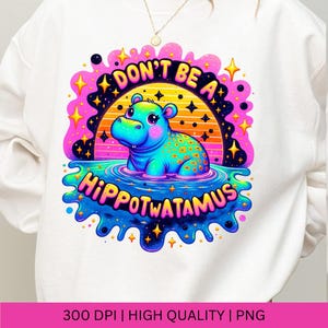 May include: A white sweatshirt with a colorful graphic design featuring a cartoon hippopotamus in a pool of water. The graphic says "Don't be a Hippoppotamus" with a retro sunset background and stars.