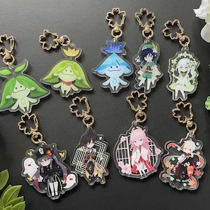 Puede incluir: Un conjunto de diez llaveros de acrílico transparente con varios personajes y diseños de anime. Los llaveros están unidos a anillos metálicos dorados y tienen un amuleto en forma de trébol en la parte superior.