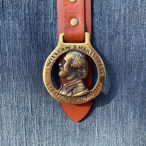 May include: A brass belt buckle with a portrait of William Shakespeare and the text "William Shakespeare Stratford Upon Avon".