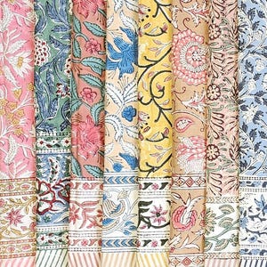 Könnte beinhalten: Eine Sammlung farbenfroher Stoffbahnen mit floralen und botanischen Mustern. Die Stoffe weisen eine Vielzahl von Farben auf, darunter Rosa, Blau, Gelb und Grün. Jedes Panel hat ein einzigartiges Design mit aufwendigen Details und Bordüren.
