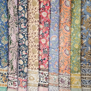 May include: A collection of eight fabric swatches featuring a variety of floral patterns in shades of blue, green, red, orange, and beige. The fabric has a traditional Indian block print design.