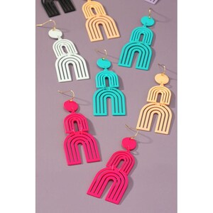May include: Assortment of colorful rainbow-shaped dangle earrings. The earrings are made of plastic and have a gold-tone hook closure. The earrings are available in pink, turquoise, white, and peach.