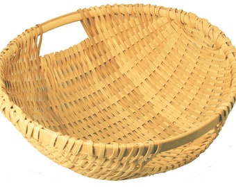 May include: A woven basket with a single handle. The basket is made of natural, light brown material and has a round shape.