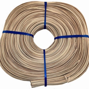 May include: A roll of natural, unpainted, flat, woven rattan cane, approximately 1/2 inch wide, tied with blue ribbon. The cane is used for crafting and weaving.