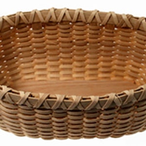 May include: A woven basket made of natural wood with a light brown color. The basket has an oval shape and a smooth, polished finish.