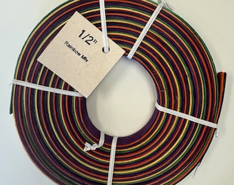 May include: A roll of 1/2 inch wide, multi-colored, woven raffia ribbon. The ribbon is a mix of purple, orange, yellow, and green colors. The label reads "1/2" Rainbow Mix".