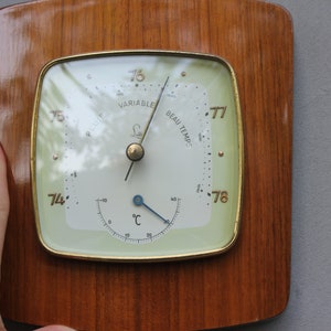 May include: A vintage wooden barometer with a round, white face and gold trim. The face has a needle pointing to "Beau Temps" and a thermometer with a blue needle. The barometer is labeled "74" to "78" and has the words "Variable" and "Beau Temps" printed on the face.
