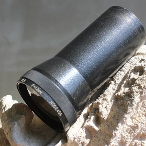 May include: A black camera lens with a silver ring and the text "F=12cm" and "N202456".