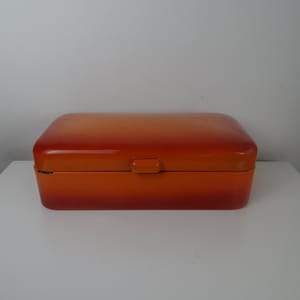 May include: Orange metal bread box with a hinged lid and a small handle on the top.
