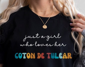 May include: A black t-shirt with the text "just a girl who loves her COTON DE TULEAR" in colourful letters.