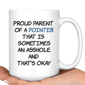 Può includere: Una tazza da caffè in ceramica bianca con testo nero che recita "Proud Parent of a Pointer That is Sometimes an Asshole and That's Okay". La parola "Pointer" è in blu.
