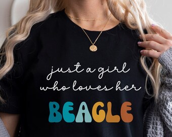 Op de afbeelding: Een zwart T-shirt met de tekst "just a girl who loves her BEAGLE" in kleurrijke retro letters.