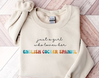 May include: A beige sweatshirt with the text "just a girl who loves her ENGLISH COCKER SPANIEL" in rainbow colors.