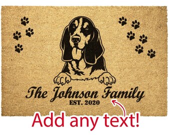 May include: A brown coir doormat with a black silhouette of a Bloodhound dog peeking over the top. The text "The Johnson Family EST. 2020" is printed on the mat, along with paw prints.