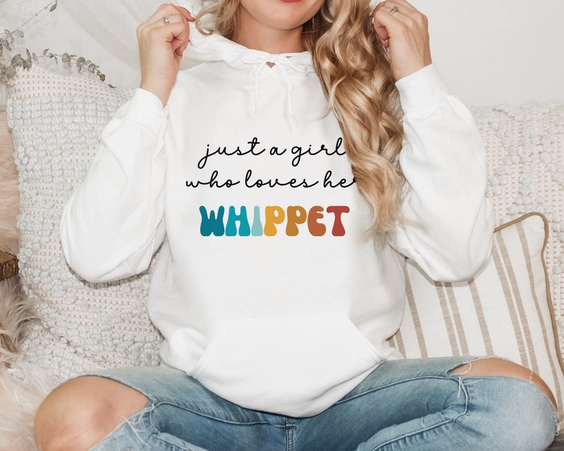 Może przedstawiać: Biała bluza z kapturem z napisem "just a girl who loves her WHIPPET" w czarnym kolorze i słowem "WHIPPET" w tęczowych kolorach.