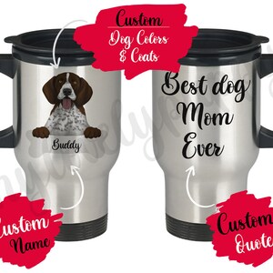 Op de afbeelding: Een reistumbler van roestvrij staal met een zwarte deksel en handvat. De beker heeft een gepersonaliseerd ontwerp met een cartoonafbeelding van een bruine en witte hond, de tekst "Buddy" en de woorden "Best dog Mom Ever".