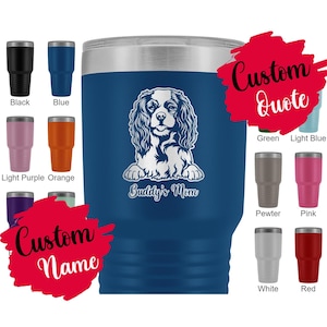 Puede incluir: Un vaso térmico azul marino con tapa plateada, con una ilustración blanca de un Cavalier King Charles Spaniel y el texto "Buddy's Mom". Se muestran opciones de color adicionales: negro, azul, lila claro, naranja, verde, azul claro, peltre, rosa, blanco y rojo.