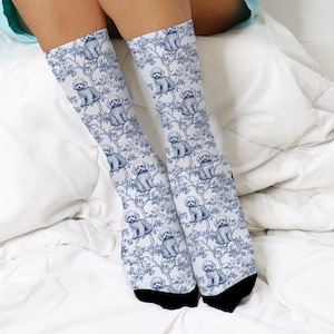 May include: A pair of knee-high socks with a repeating pattern of small, seated poodle illustrations in blue on a white background. The socks also feature a blue floral design. The socks have black heels and toes.