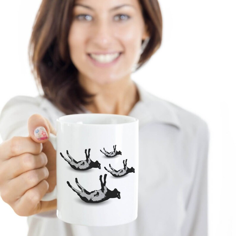 May include: White ceramic mug with a black and white graphic of four sheep falling from the sky.