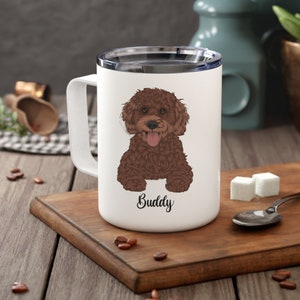 Puede incluir: Taza de viaje de cerámica blanca con una ilustración de un caniche marrón y el nombre "Buddy" impreso en la parte inferior.