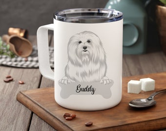 Puede incluir: Taza de viaje blanca con una ilustración de un perro blanco y esponjoso. El perro sostiene un letrero con forma de hueso que dice "Buddy". La taza tiene un asa blanca y una tapa plateada. La taza está sobre una superficie de madera.