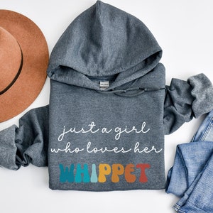 Może przedstawiać: Szara bluza z kapturem z napisem "just a girl who loves her WHIPPET" w białym i kolorowym kolorze. Litery są w retro stylu czcionki.