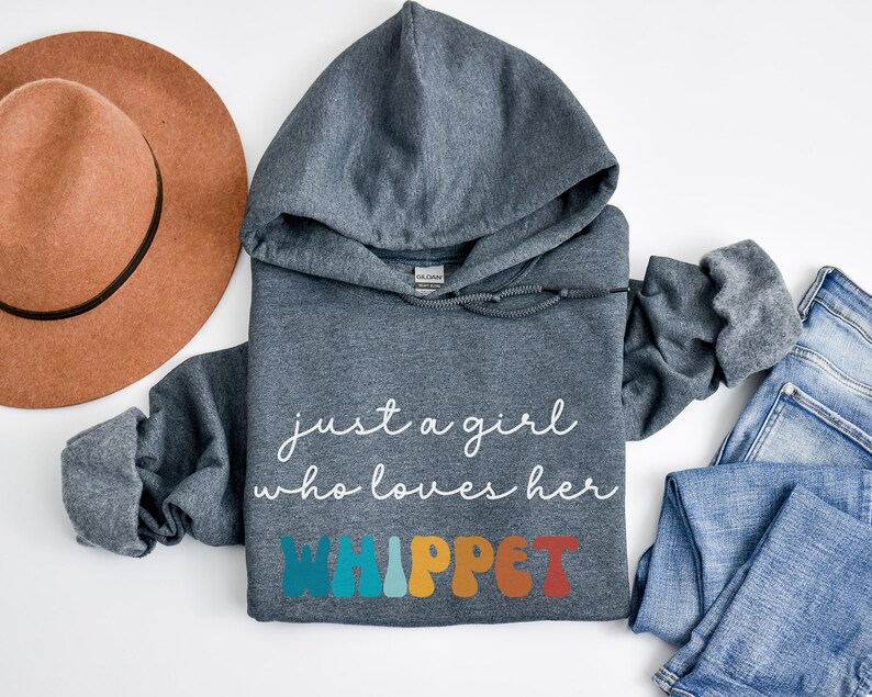 Może przedstawiać: Szara bluza z kapturem z napisem "just a girl who loves her WHIPPET" w białym i kolorowym kolorze. Litery są w retro stylu czcionki.