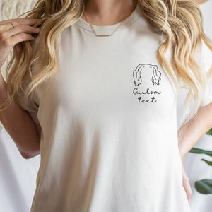 May include: White t-shirt with a line drawing of a dog's head and the text "Custom text" on the front.