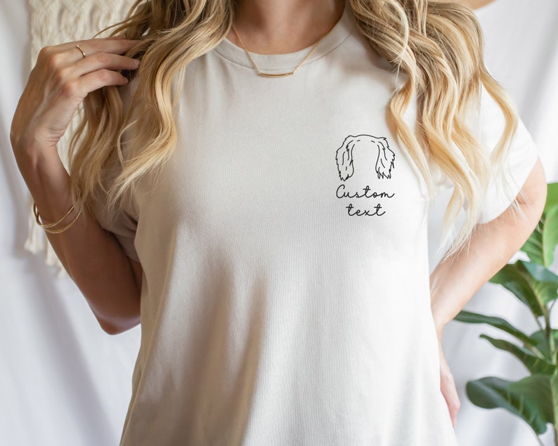 May include: White t-shirt with a line drawing of a dog's head and the text "Custom text" on the front.
