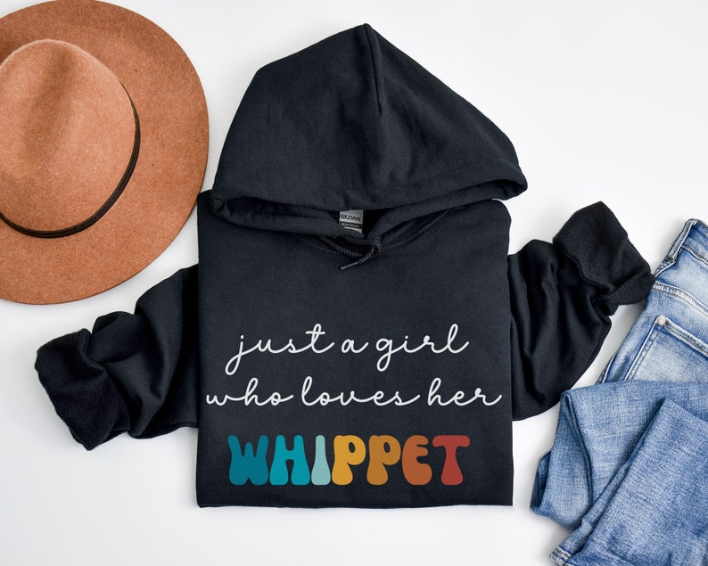 Może przedstawiać: Czarna bluza z kapturem z napisem "just a girl who loves her WHIPPET" w białym kolorze i słowem "WHIPPET" w kolorach tęczy.