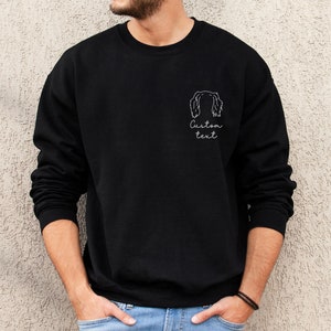 May include: Black sweatshirt with a white outline of a dog's head and the text "Custom text" on the front.